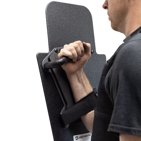 Backside view of man holding black 15" x 25" Caliber Armor Pistol rated Level IIIA HG2 Ballistic Shield with pivoting handle on a white background 8