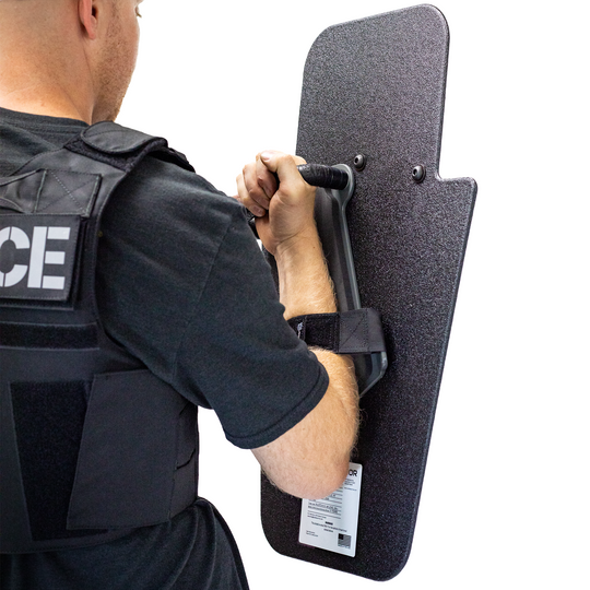 Backside view of man holding black 15" x 25" Caliber Armor Pistol rated Level IIIA HG2 Ballistic Shield with pivoting handle for left handed shooter on a white background 9