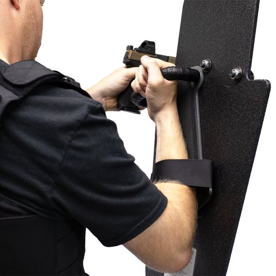 left handed officer holding a 15" x 25" Caliber Armor Rifle rated Level III+ RF2 Ballistic Shield with pivoting handle mounted for right handed use aiming through a pistol with sight  6