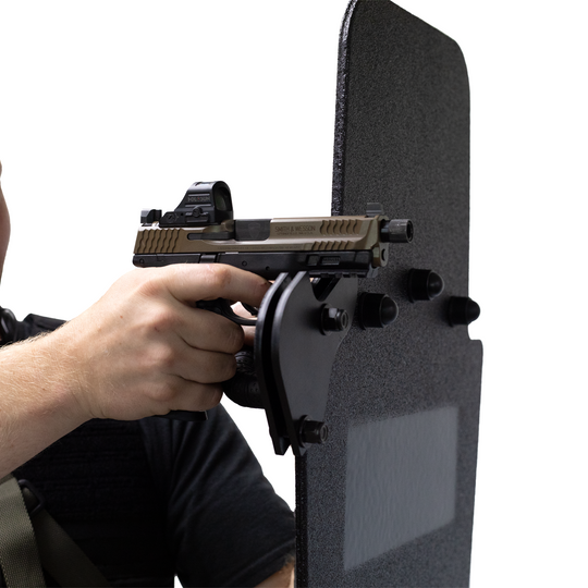 Hand holding a handgun against a black protective shield using the bolt on gun support bracket on a white background 4