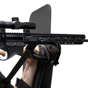 Close-up of a rifle with a scope resting on a support bracket that is mounted to a bulletproof shield 5