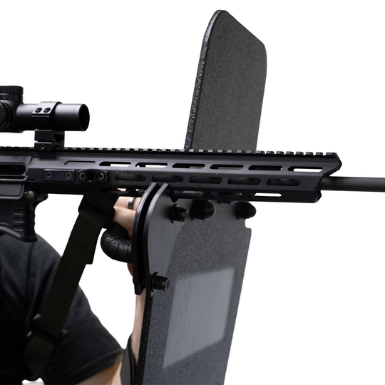 Close-up of a rifle being supported by a ballistic shield that has a ambidextrious weapon support bracket attached 6
